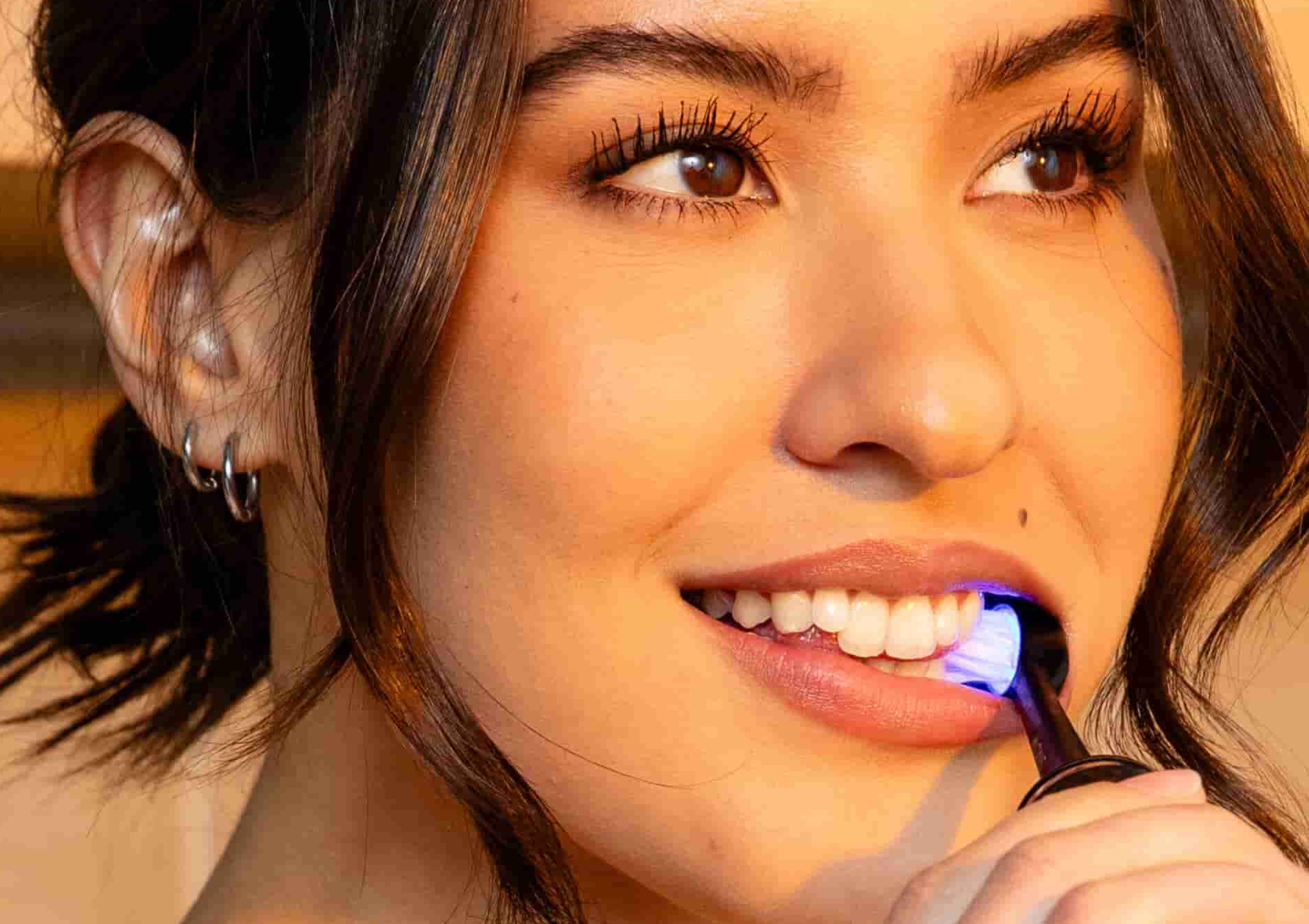 Person using a teeth whitening device with a blue light.